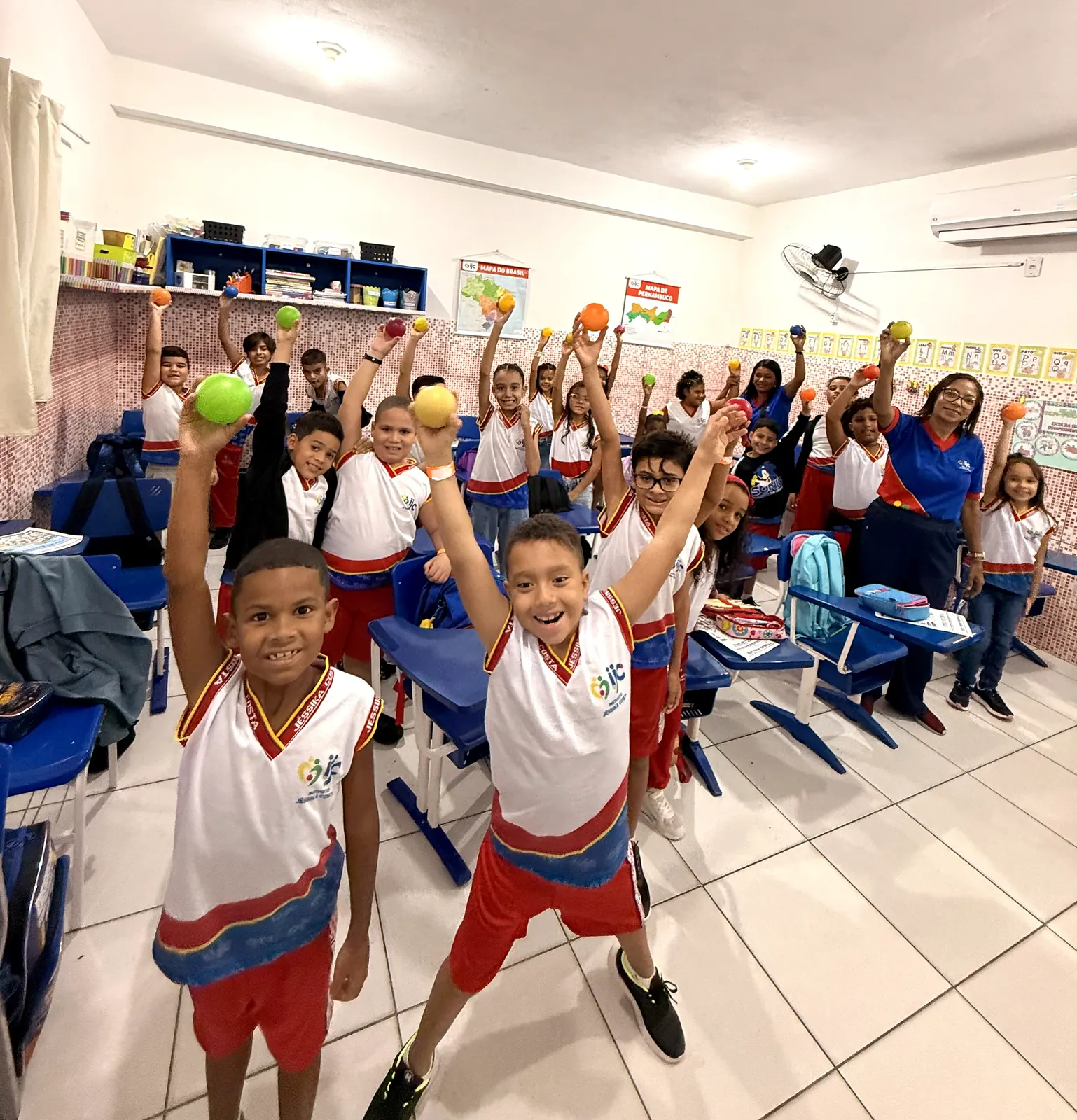 Turma e educadora participando de uma atividade com bolas coloridas.