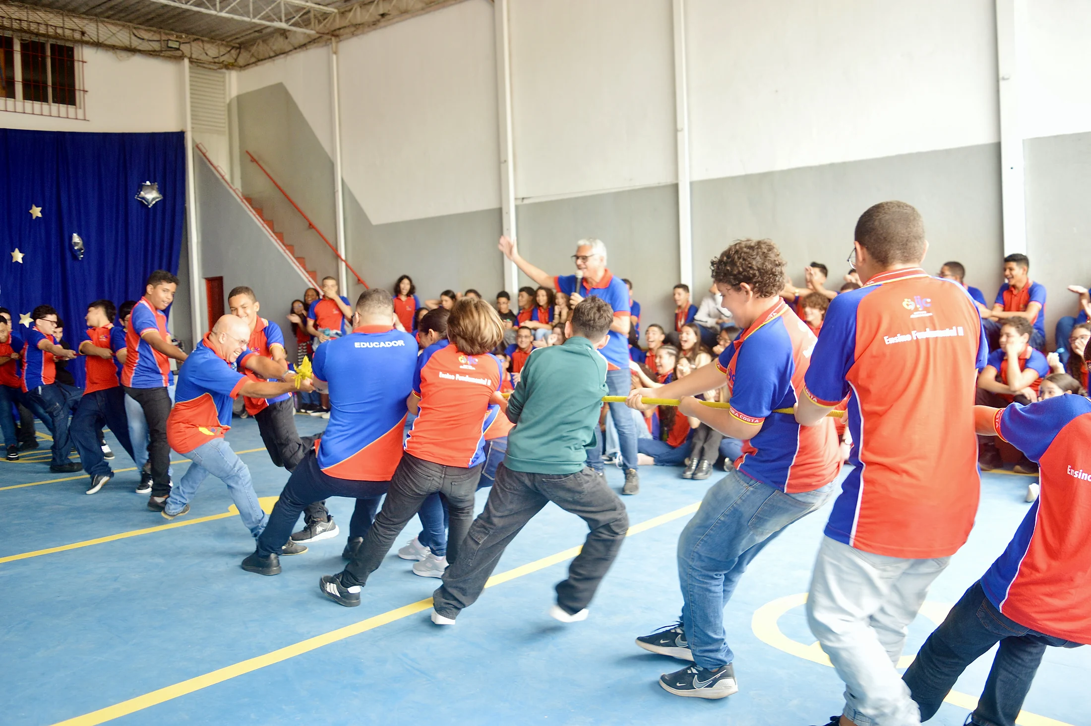 Participantes brincando de cabo de guerra na quadra.