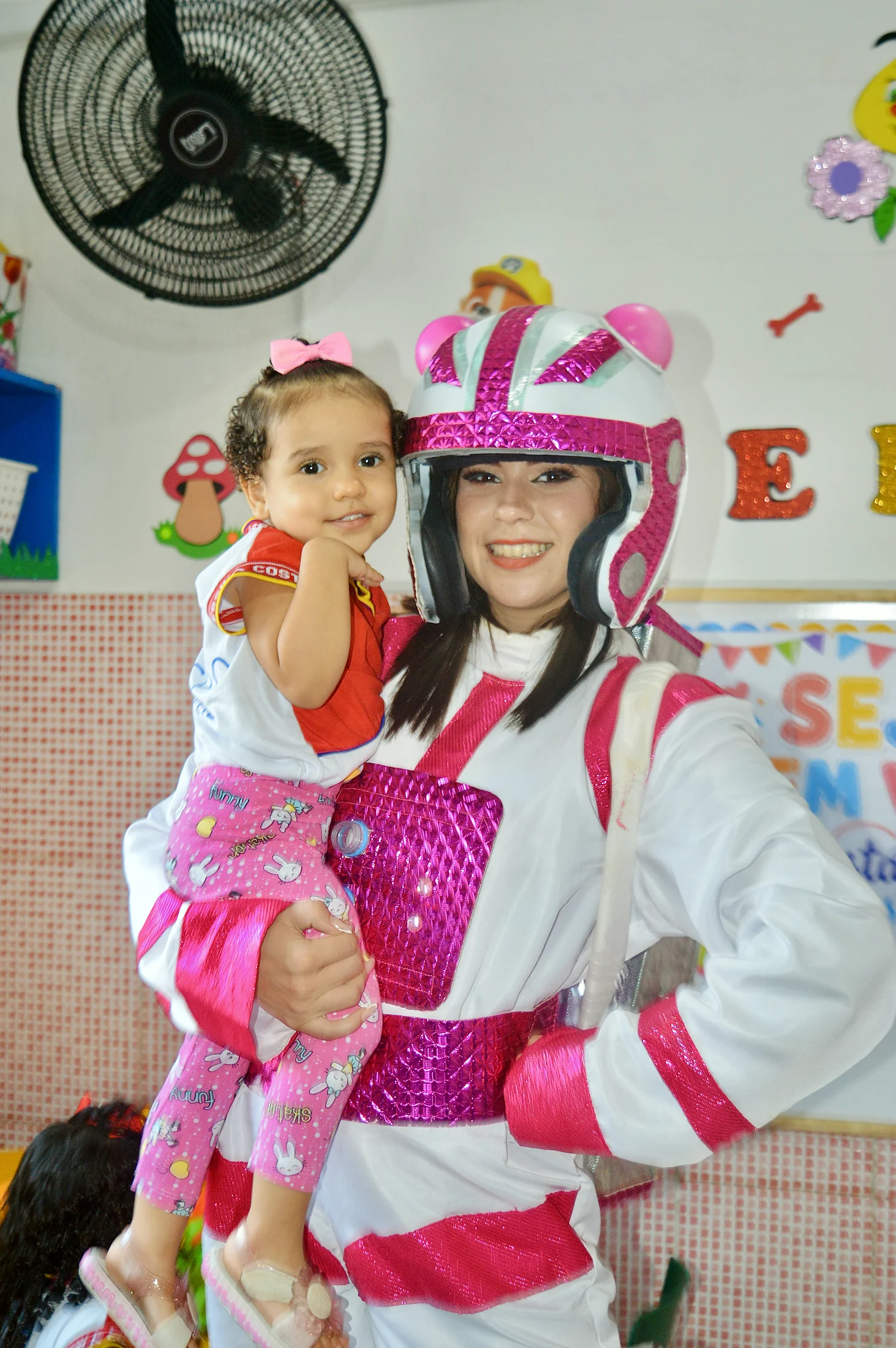 Criança no colo de uma adulta fantasiada em uma celebração.