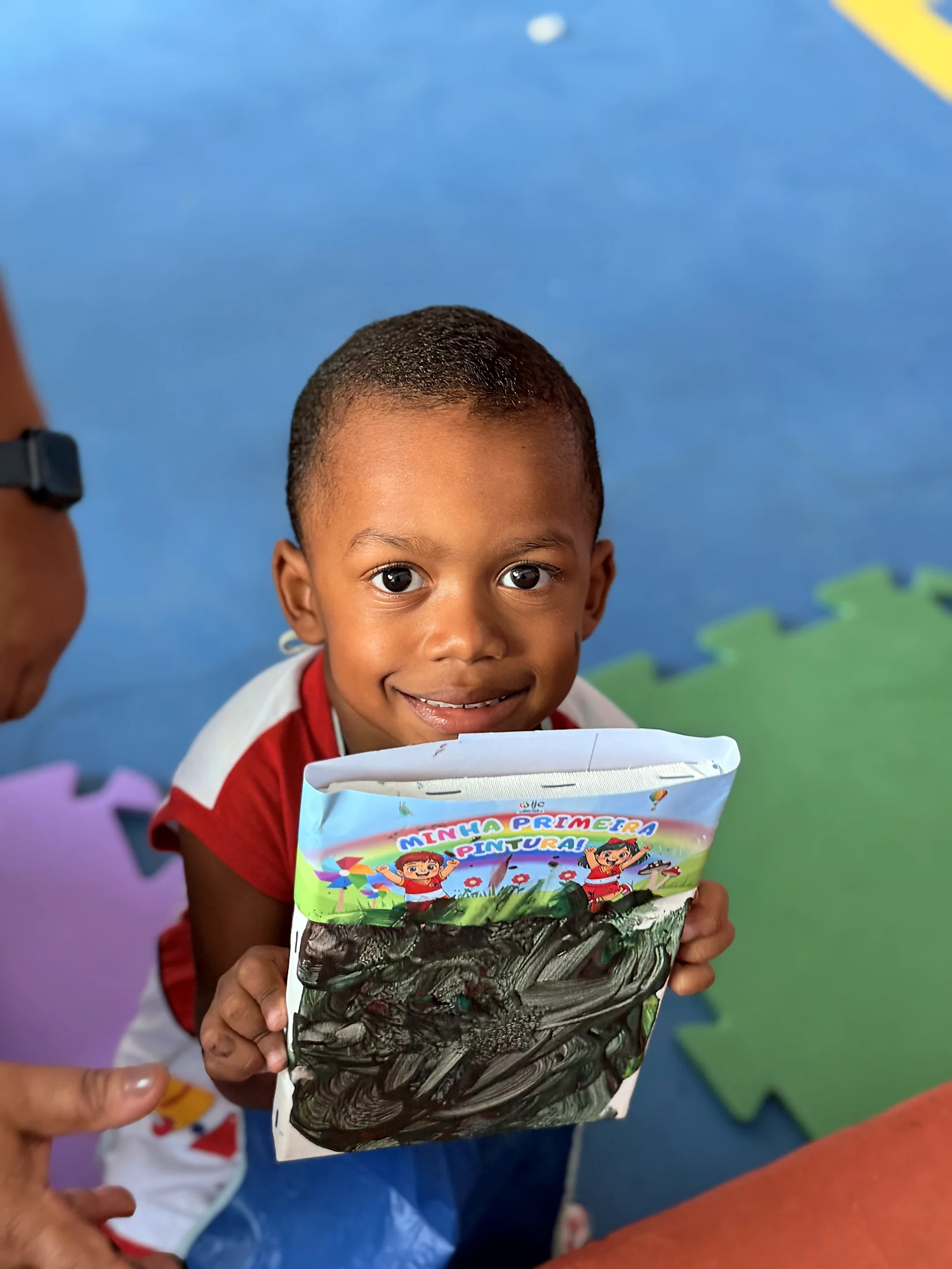 Estudante sorrindo com um livro nas mãos.